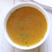 Homemade chicken broth is served in a white bowl.