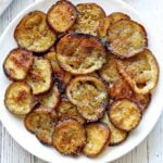 Eggplant chips are piled on a white plate.