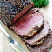 A sliced ribeye roast is served on a cutting board.