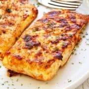 Grilled halibut is served on a white plate with a fork.