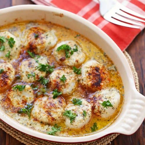 Baked scallops are served in an oval dish.