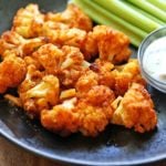 Buffalo cauliflower is served with celery and a dipping sauce.