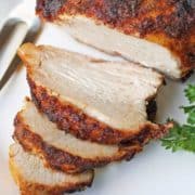 Roasted boneless turkey breast is served on a white plate.