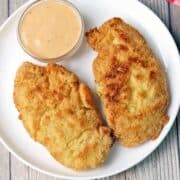 Gluten-free chicken tenders are served with a dipping sauce.