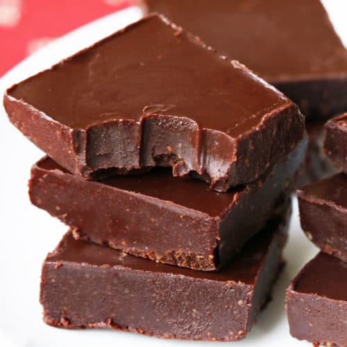 Keto fudge squares are stacked on a white plate.