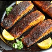 Blackened salmon is served with lemon slices.