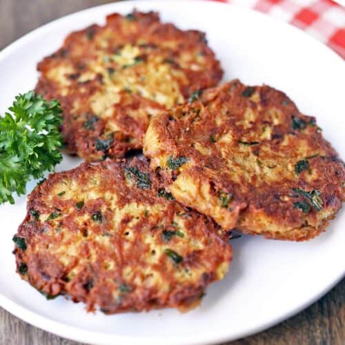 Three tuna patties are served on a white plate, garnished with parsley.
