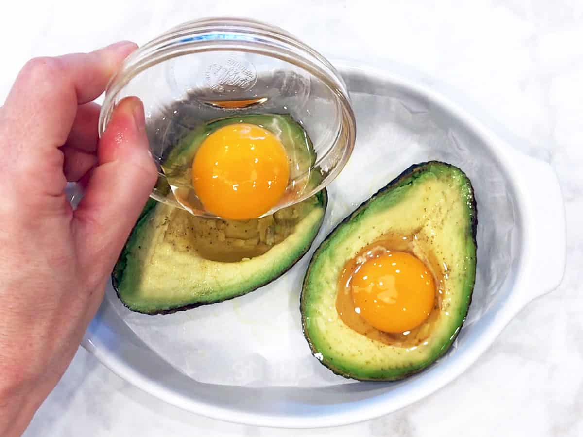 Pouring an egg into the avocado. 