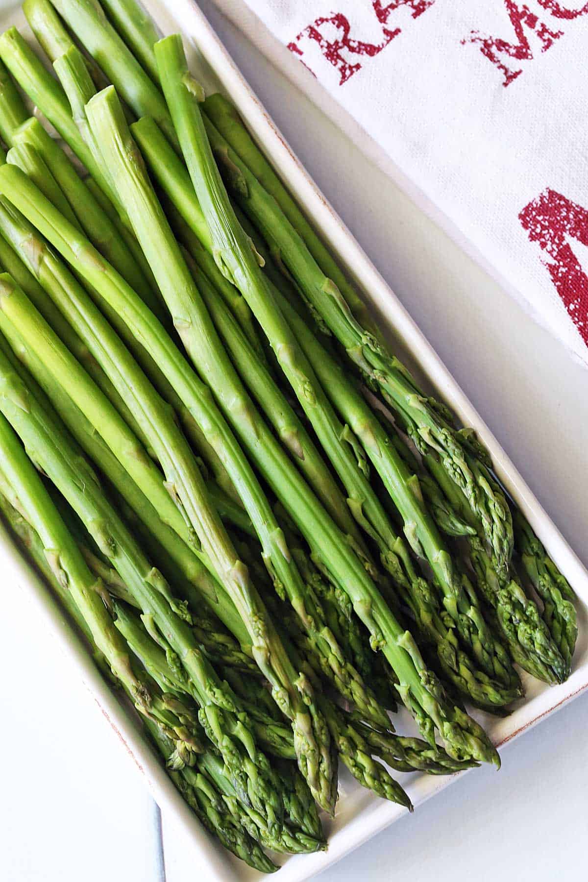 Microwave asparagus is served on a white tray. 