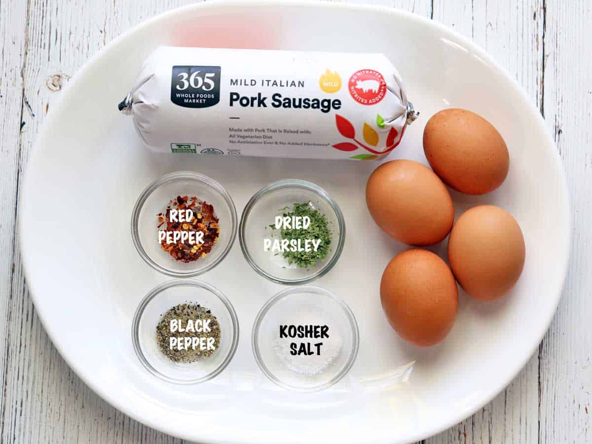 Sausage egg muffins ingredients are arranged on a white platter. 