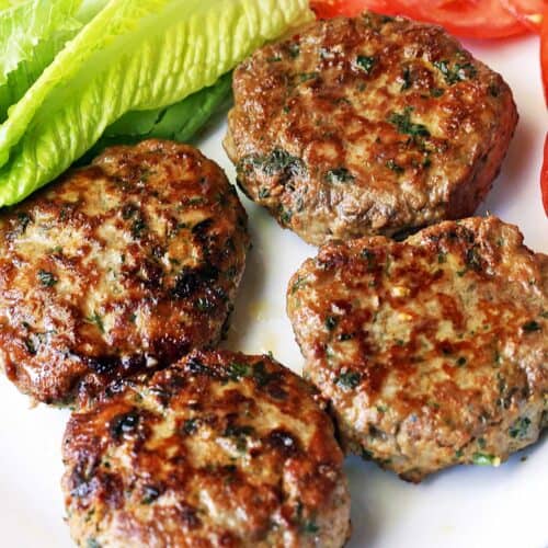 Turkey burgers are served with lettuce and sliced tomatoes.