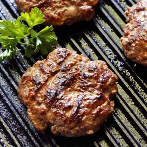 Grilled burgers are photographed on the grill.