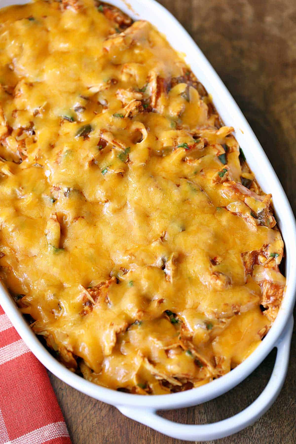 Keto enchilada casserole is served in a white baking dish with a red napkin. 
