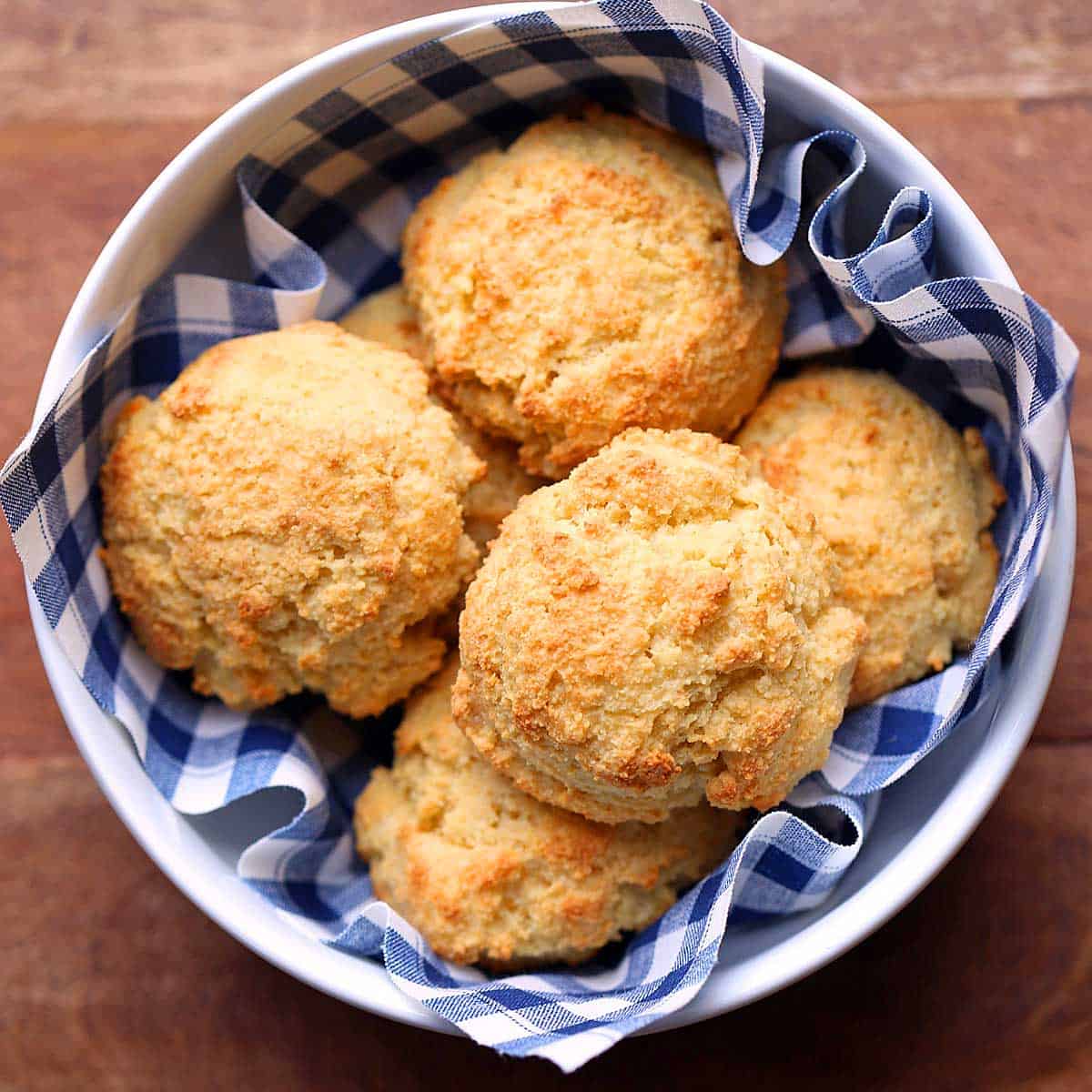 Keto cheese biscuits are served in a bowl lined with a blue-and-white napkin. 