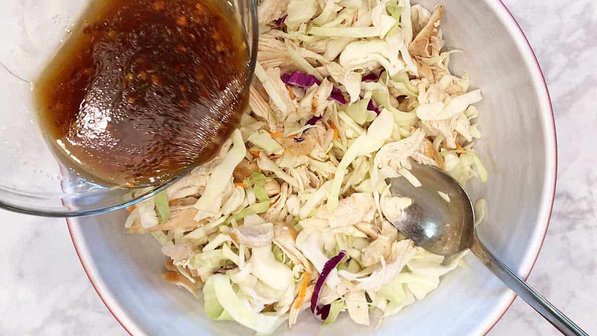 Adding the dressing to the salad. 