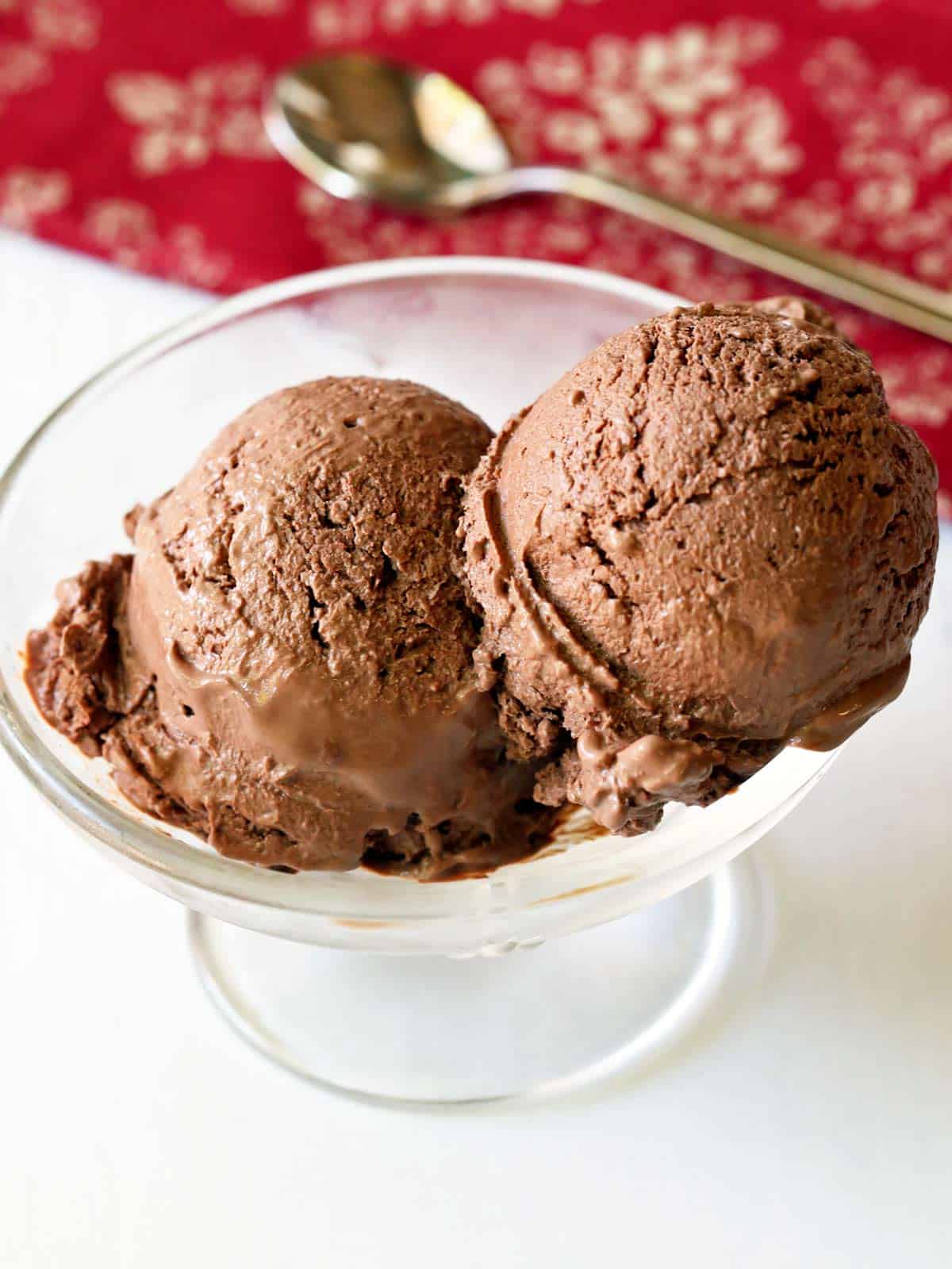 Chocolate frozen yogurt is served in a glass dessert bowl with a spoon.