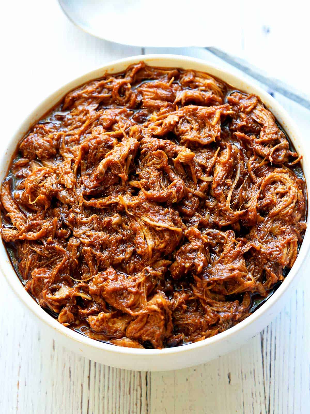 Pulled pork is served in a white bowl. 