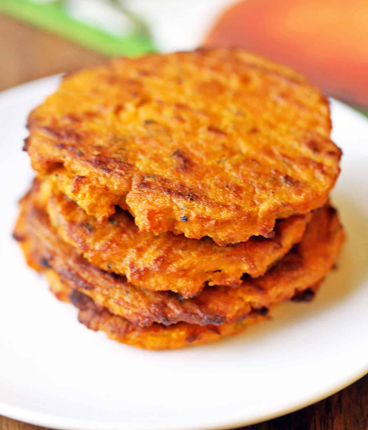 Sweet potato cakes are stacked on a white plate. 