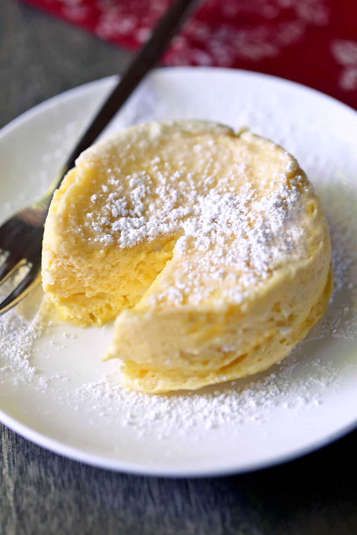 Microwave cheesecake is served on a white plate with a fork. 