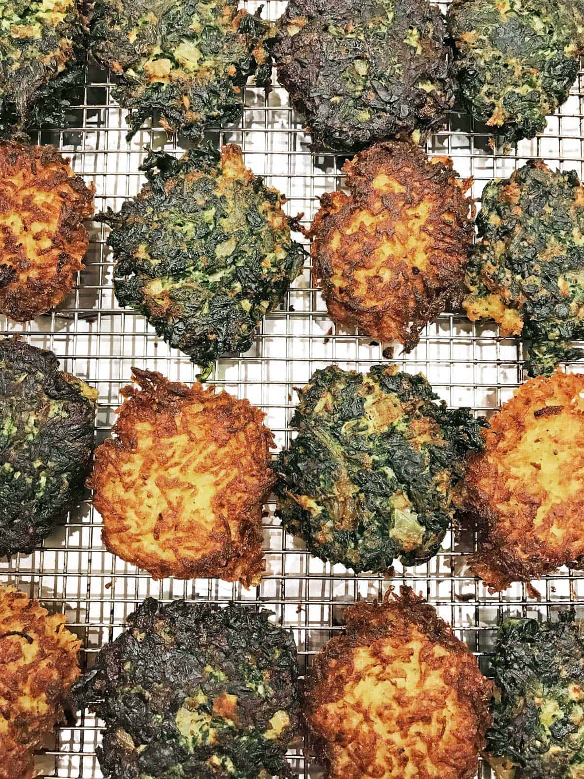 Potato and spinach latkes arranged on a baking sheet. 