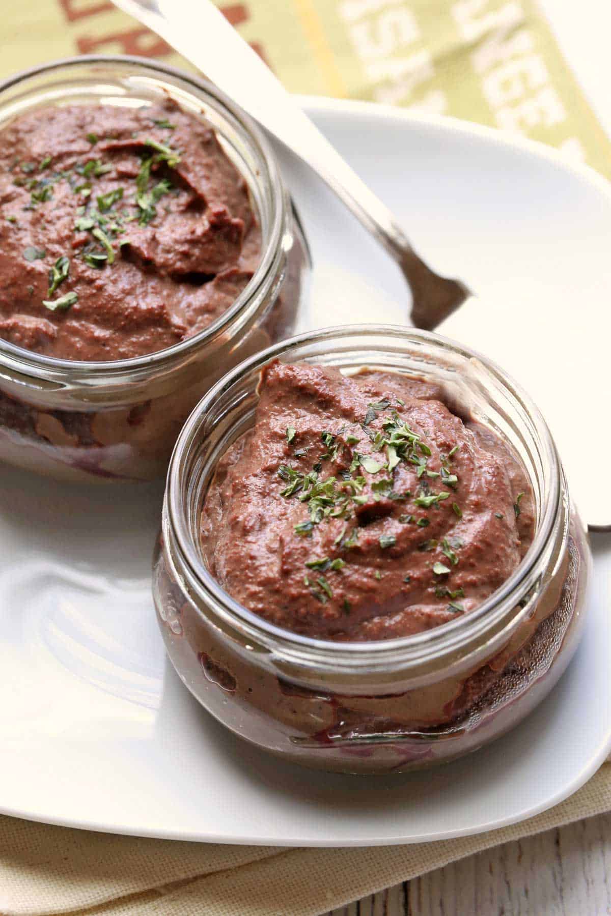Chicken liver pâté is served in jars and topped with parsley.