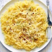 Spaghetti squash pasta is served on a white plate with a fork.
