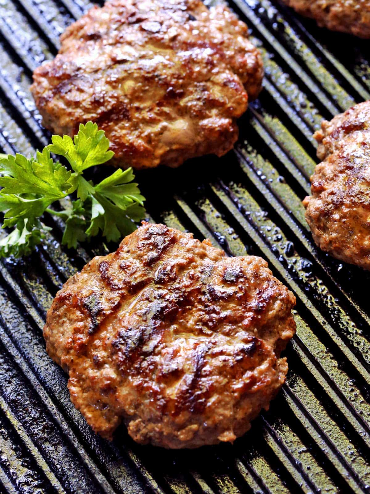 Grilled burgers are photographed on the grill.