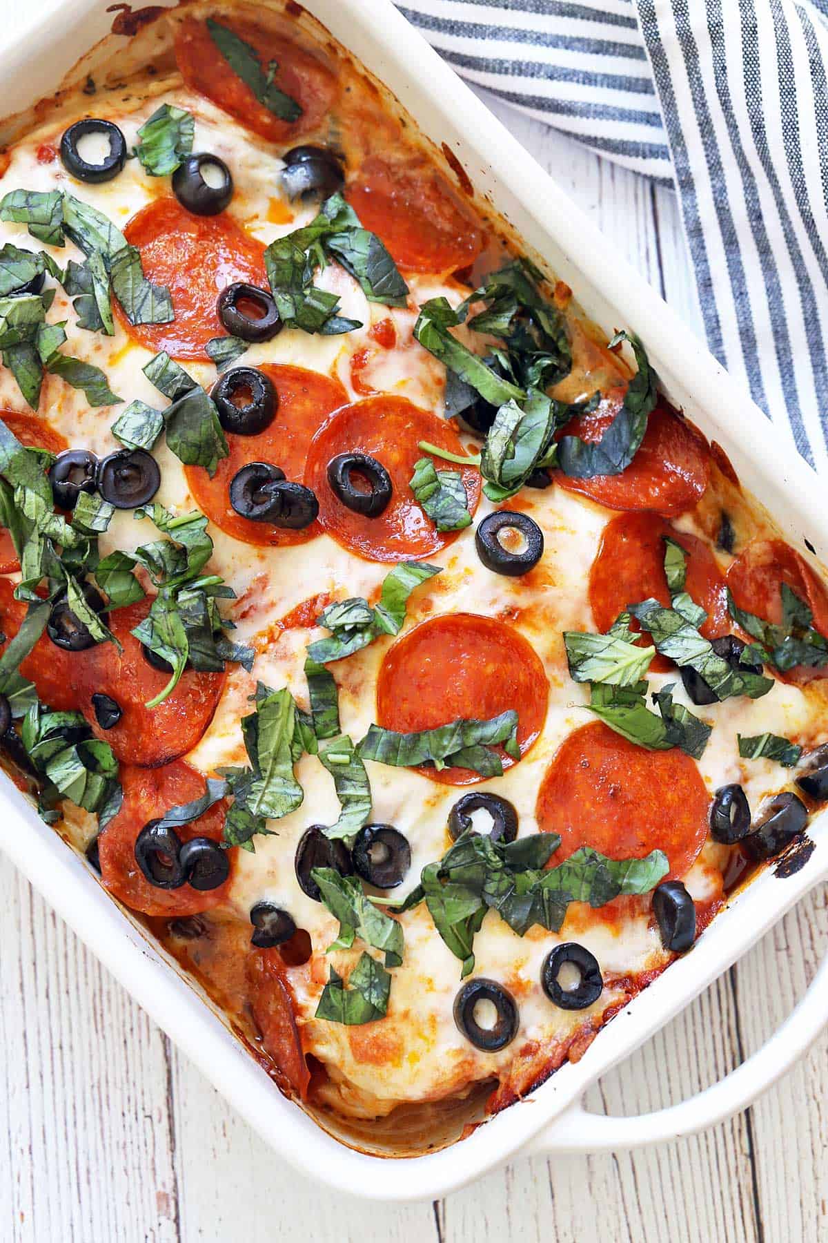 Pizza chicken is served in a white baking dish. 