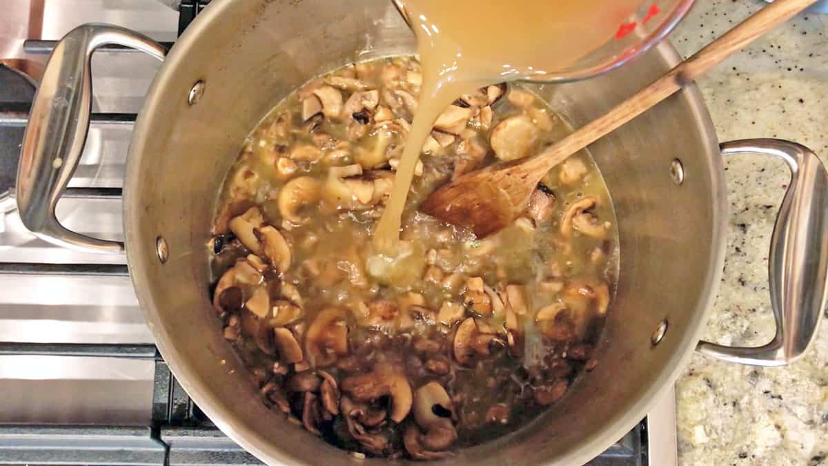 Adding broth to the stockpot. 