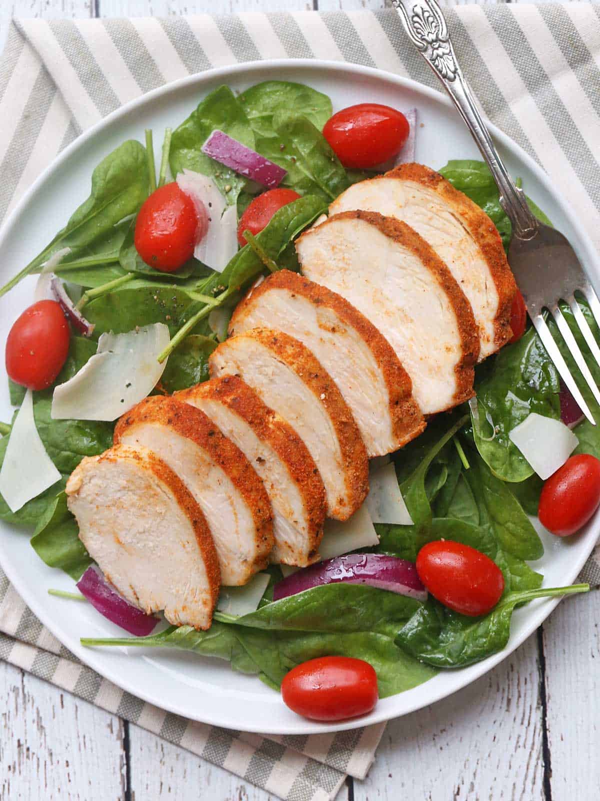 A salad topped with leftover baked chicken breast. 