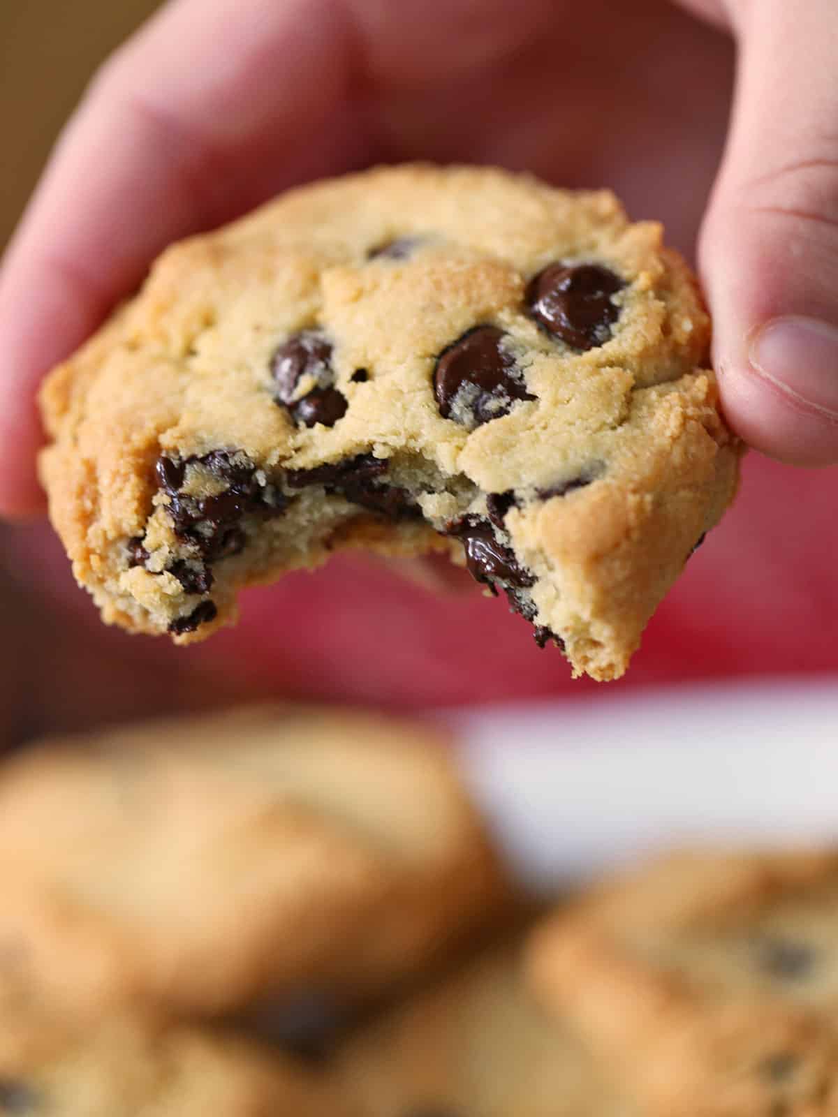 A hand is holding a keto chocolate chip cookies with a bite.
