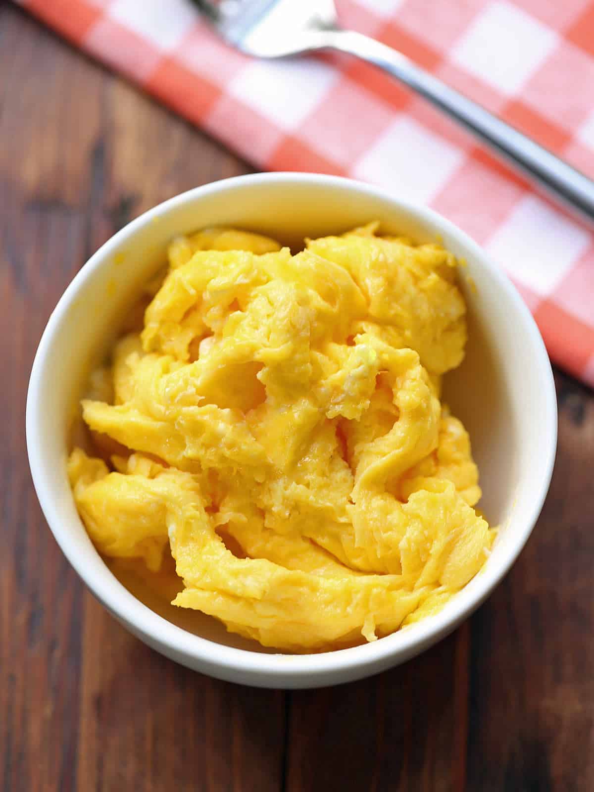 Microwave scrambled eggs are served in a white bowl. 