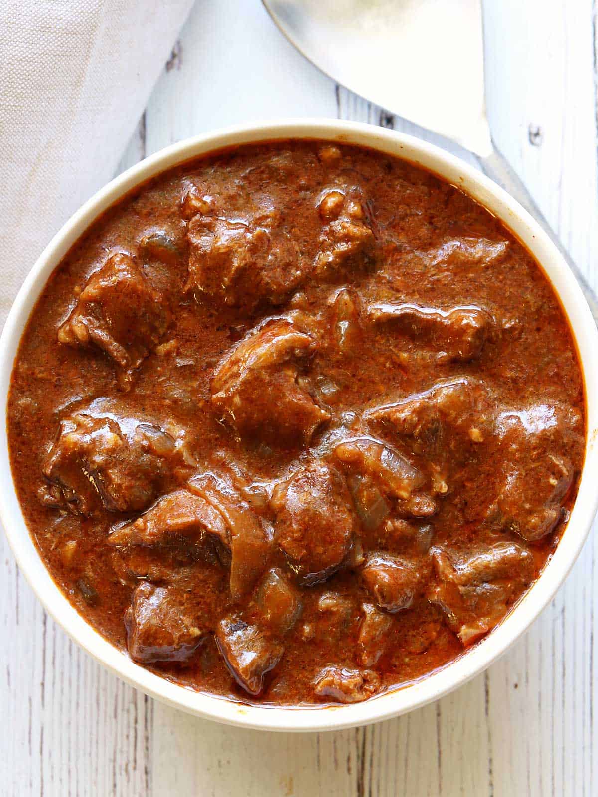 Slow cooker goulash is served in a white bowl. 