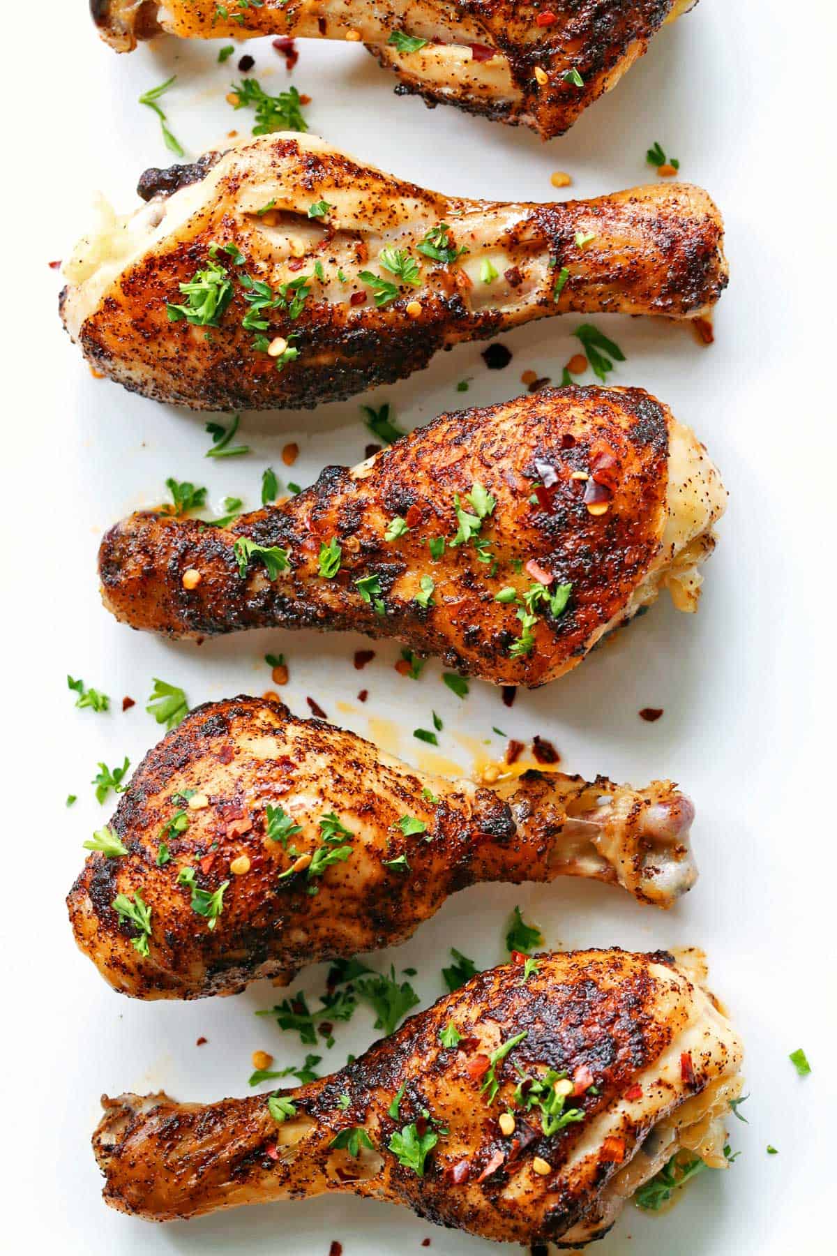 Spicy drumsticks are served on a white plate. 
