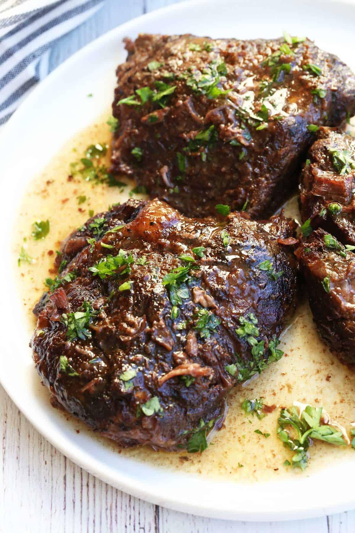 Beef cheeks are served on a white plate.