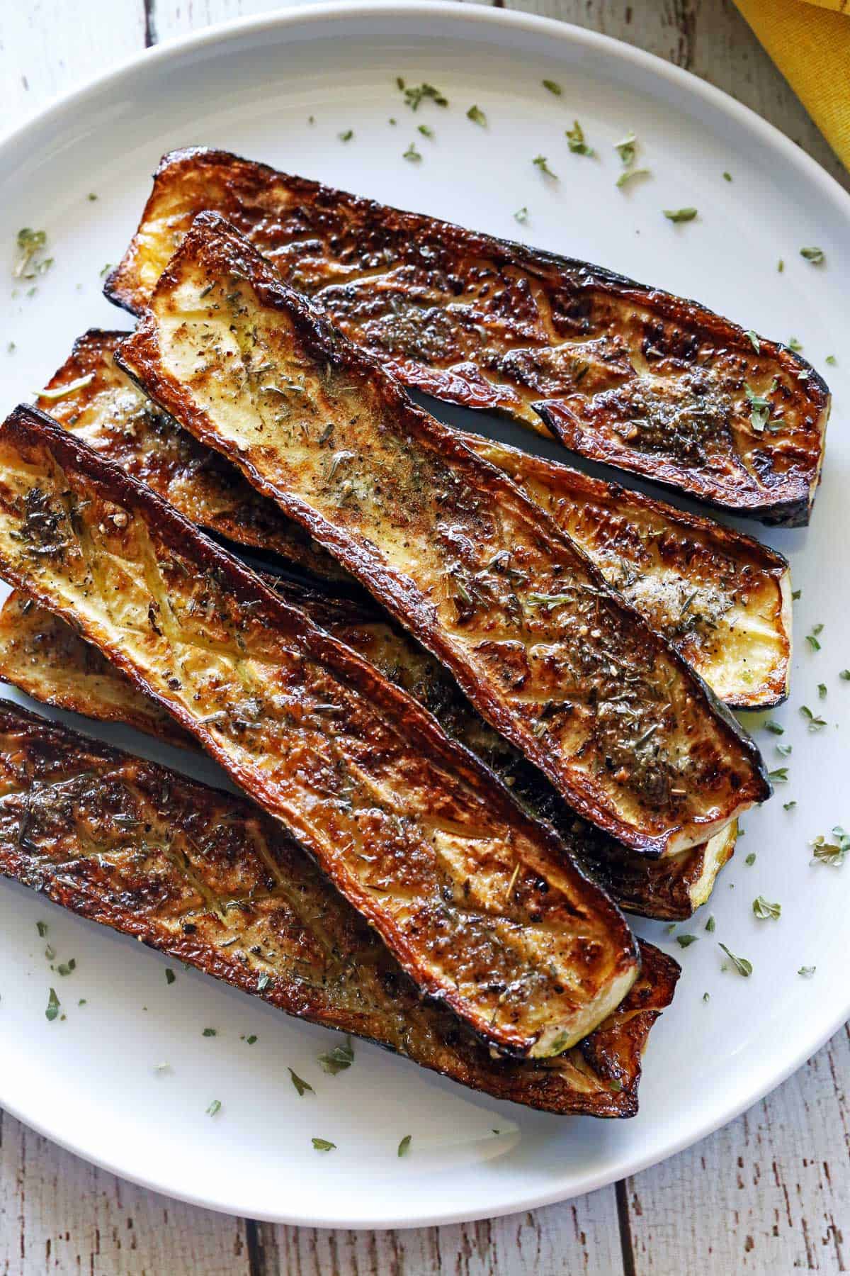 Roasted zucchini is served on a white plate. 