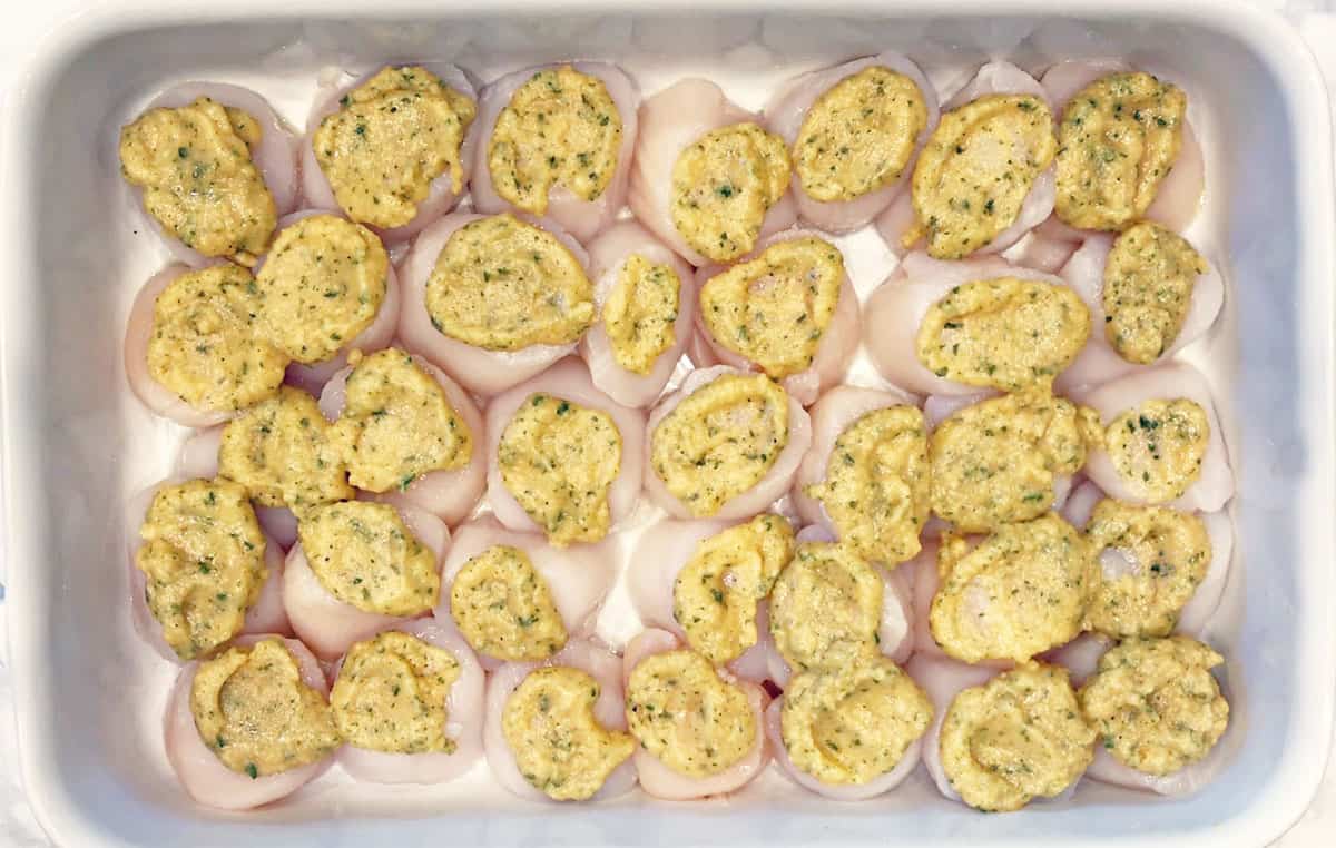 Topping the scallops with the butter mixture.