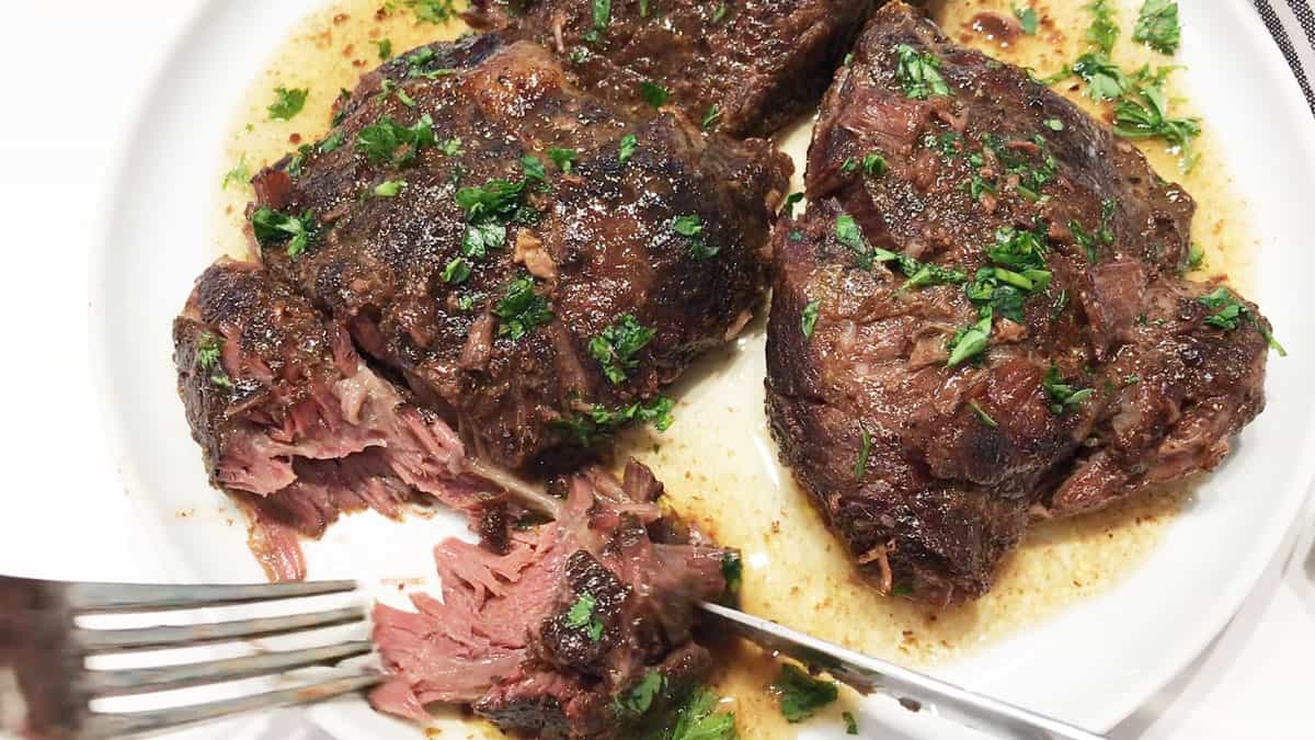 A fork showing the tender inside of a cooked beef cheek. 