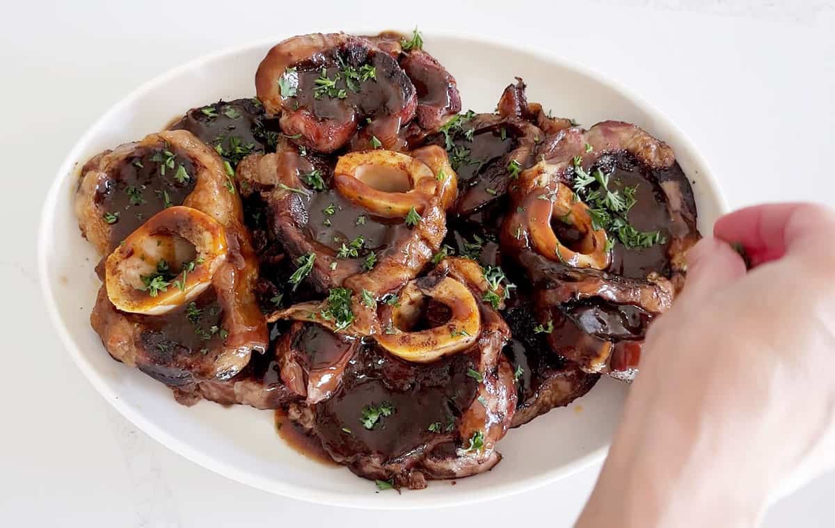 Garnishing beef shanks with parsley. 