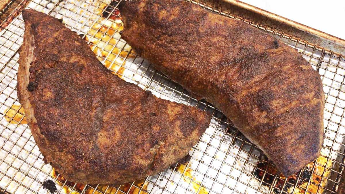 Two fully cooked  tri-tip roasts in a pan. 
