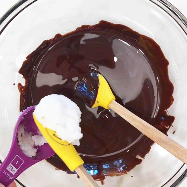 Adding coconut oil to the melted chocolate.
