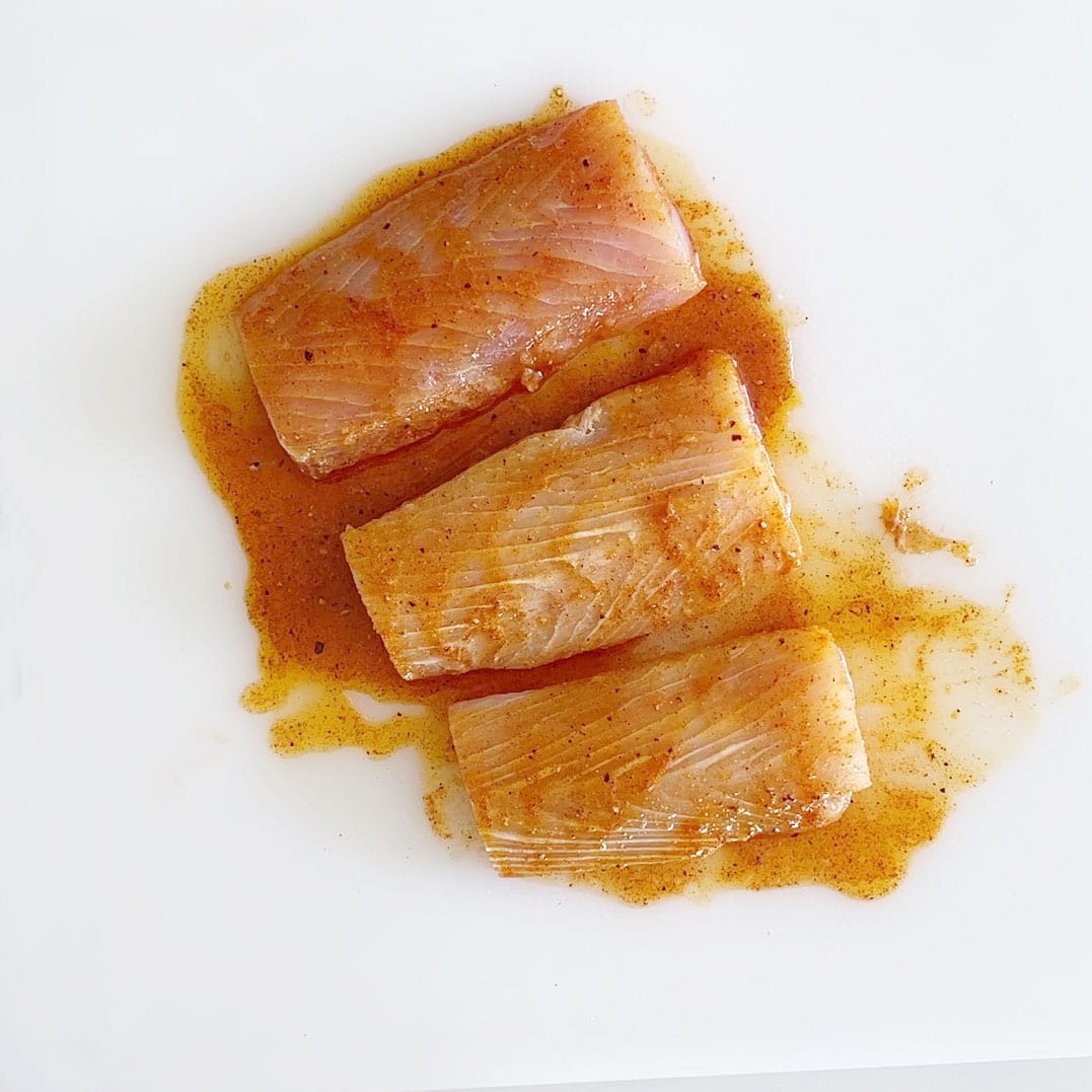 Coating the fish in the marinade. 