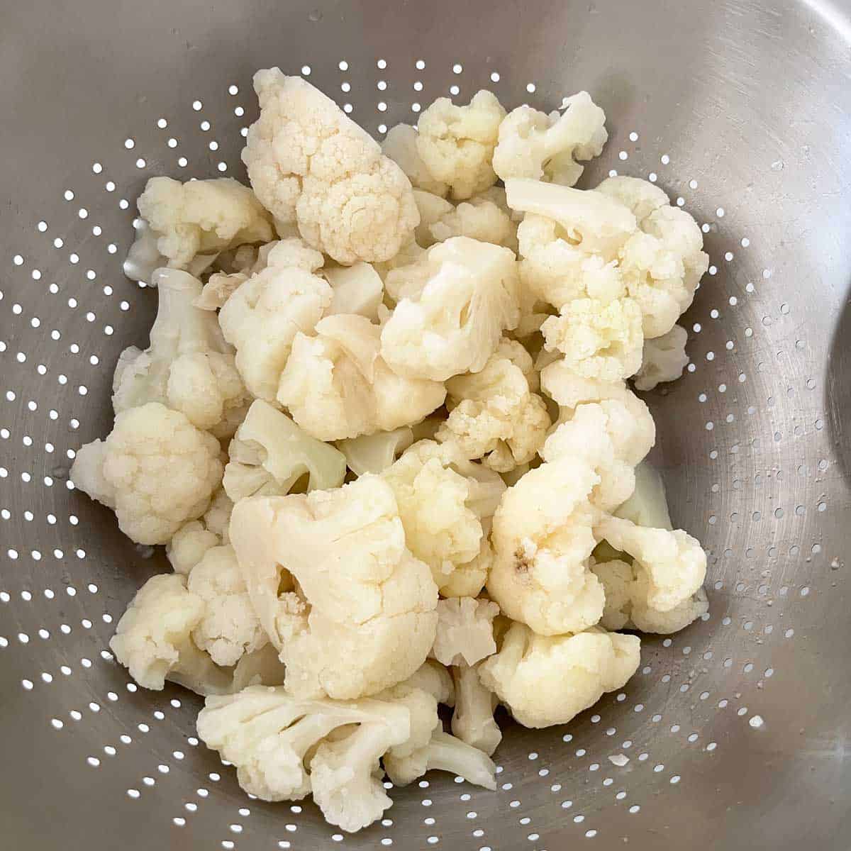 Thawed cauliflower florets in a colander. 