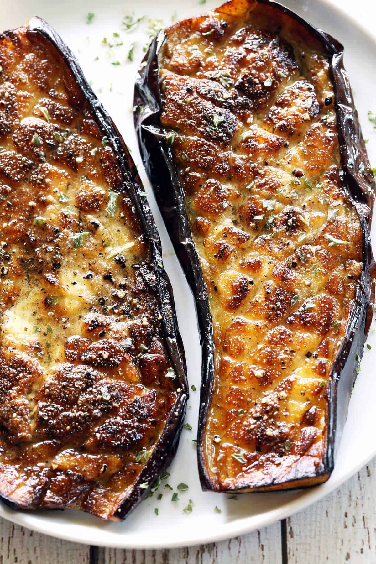 Roasted eggplant is served on a white plate. 