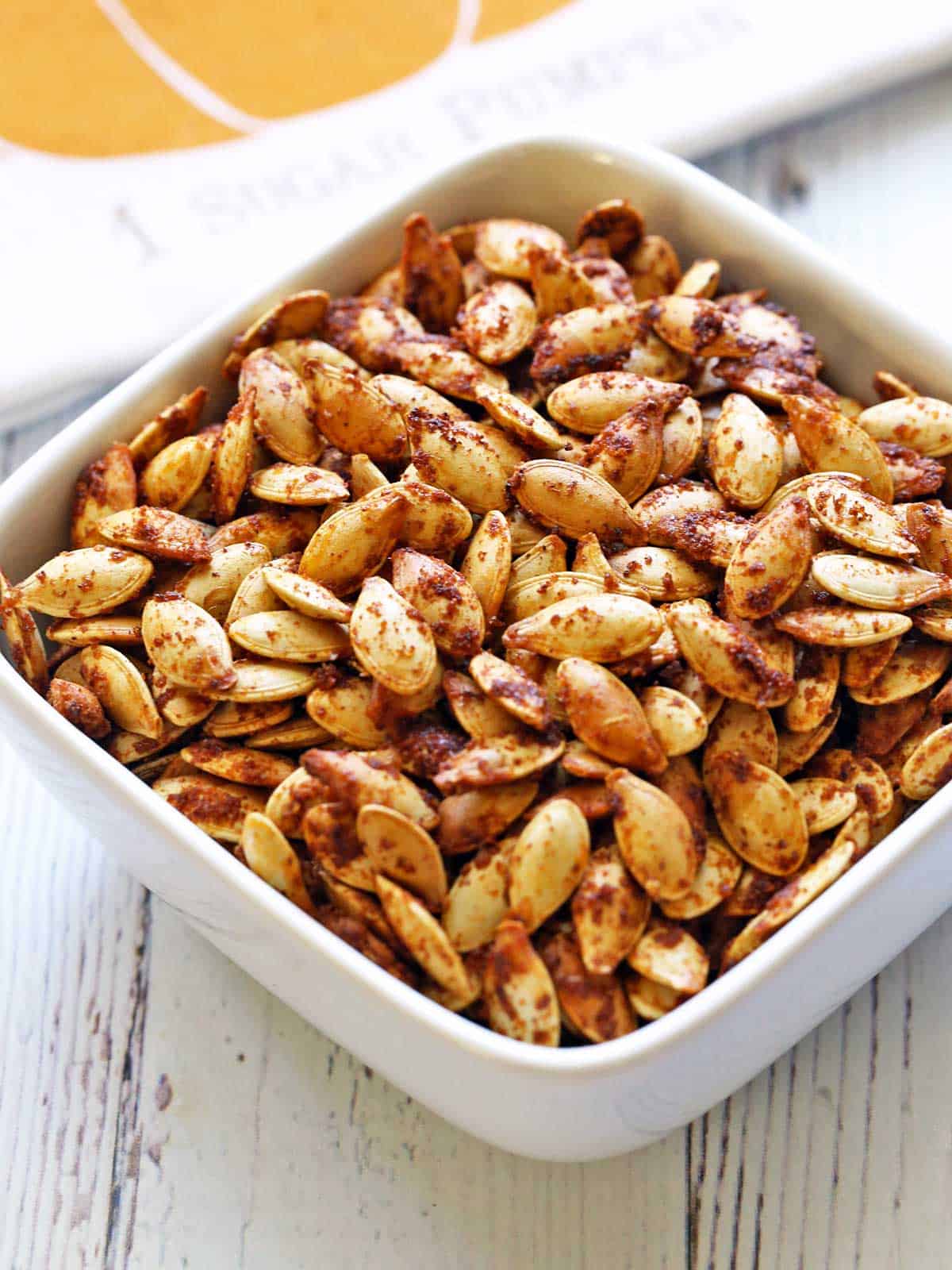 Roasted pumpkin seeds are served in a white bowl. 