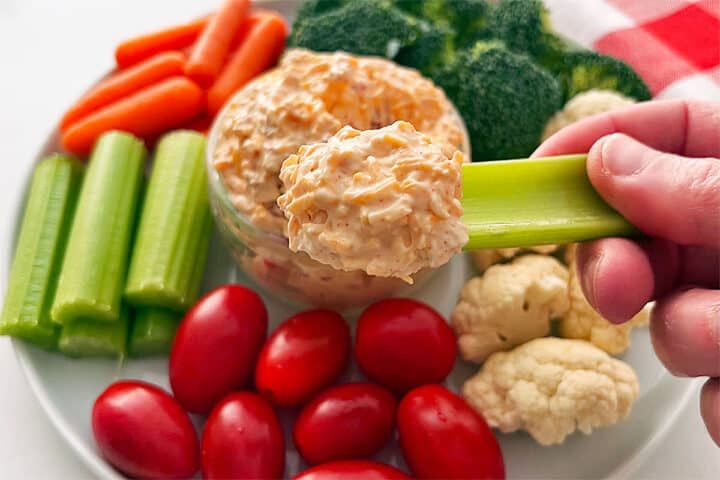 Scooping out cream cheese dip with a celery stick.