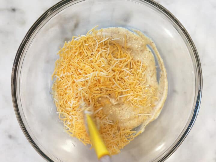 Adding grated cheese to the sauce.