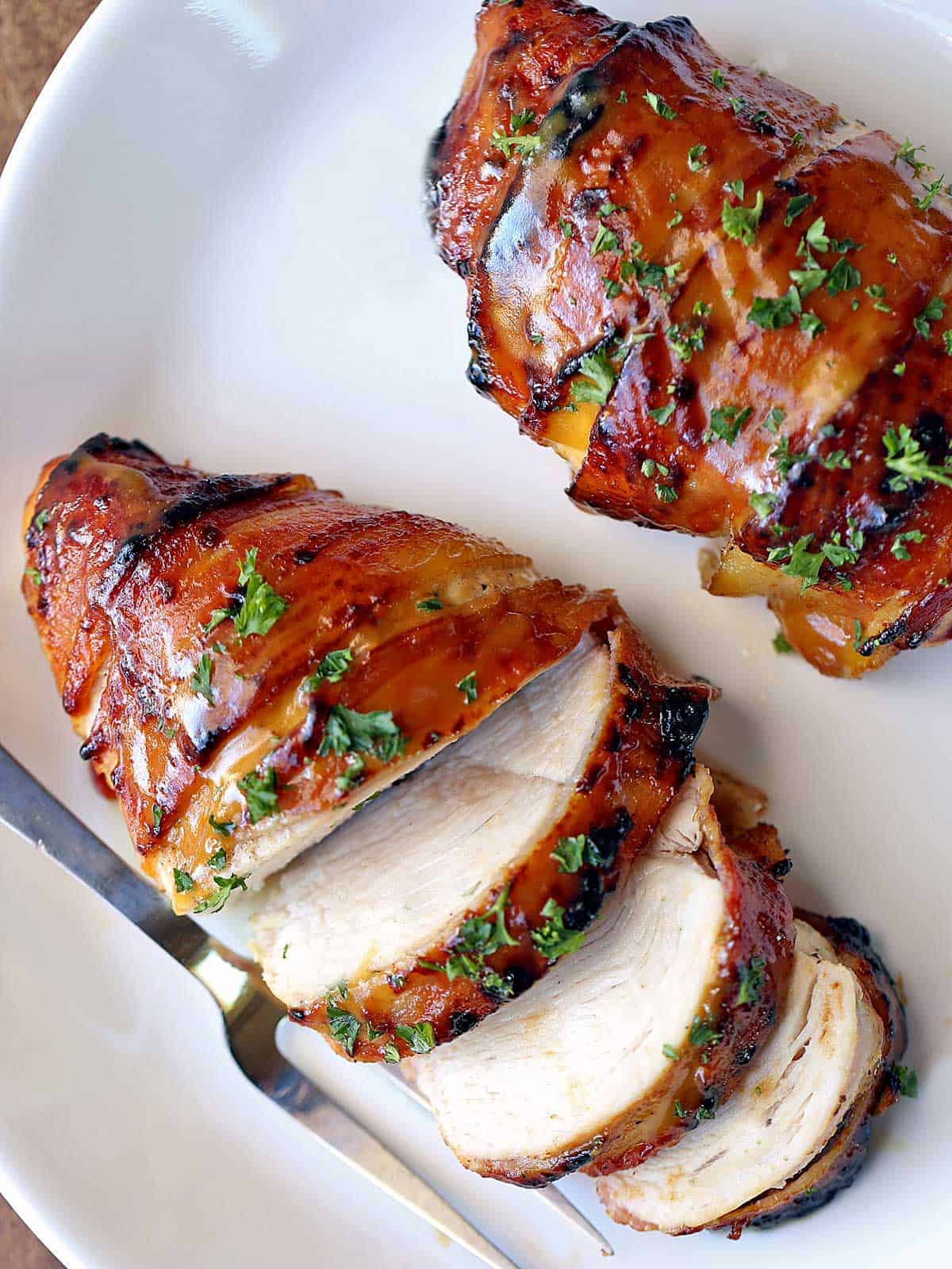 Bacon-wrapped chicken breast is served on a white plate.