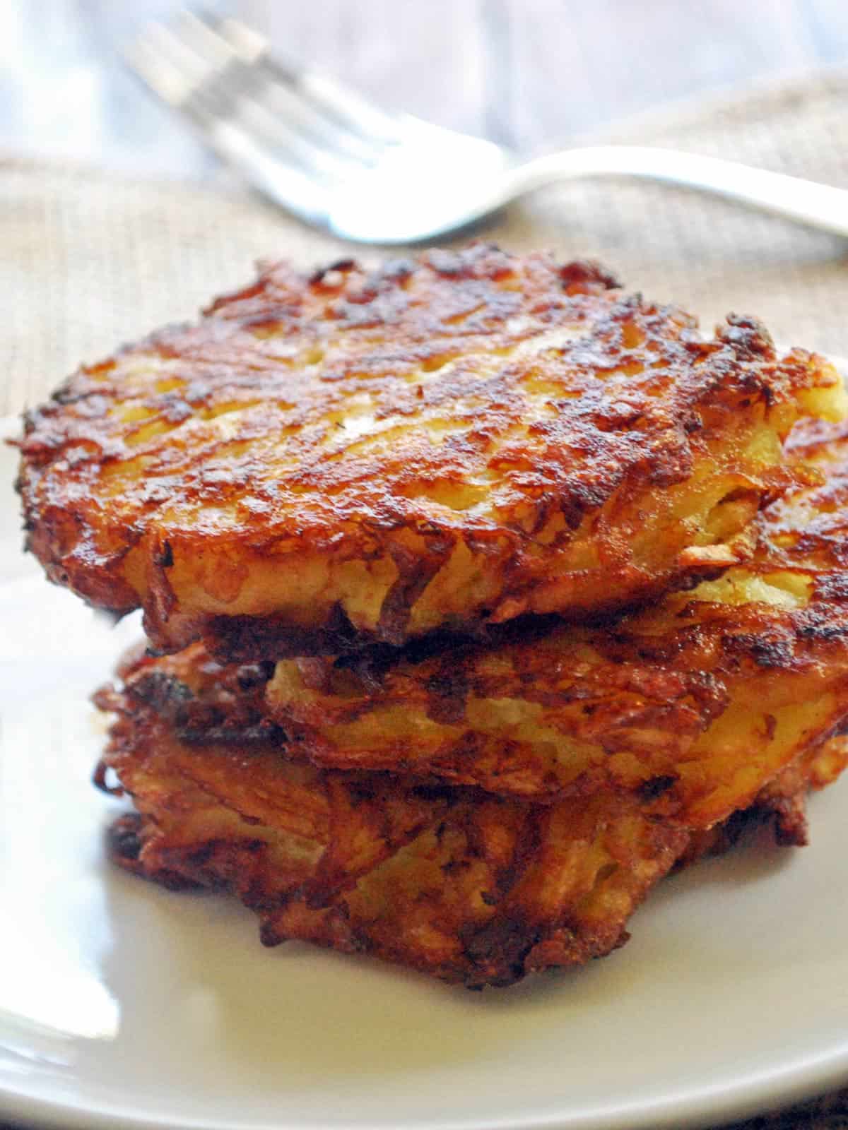 Baked latkes are served on a plate with a serving fork.