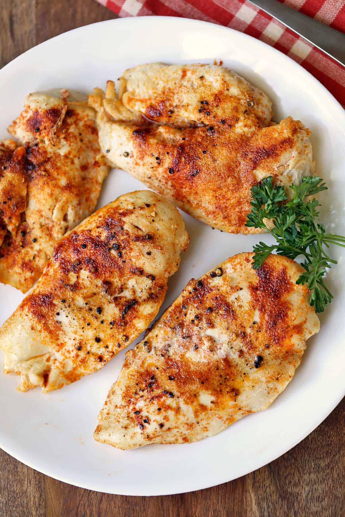 Four pieces of broiled chicken are served on a white plate.